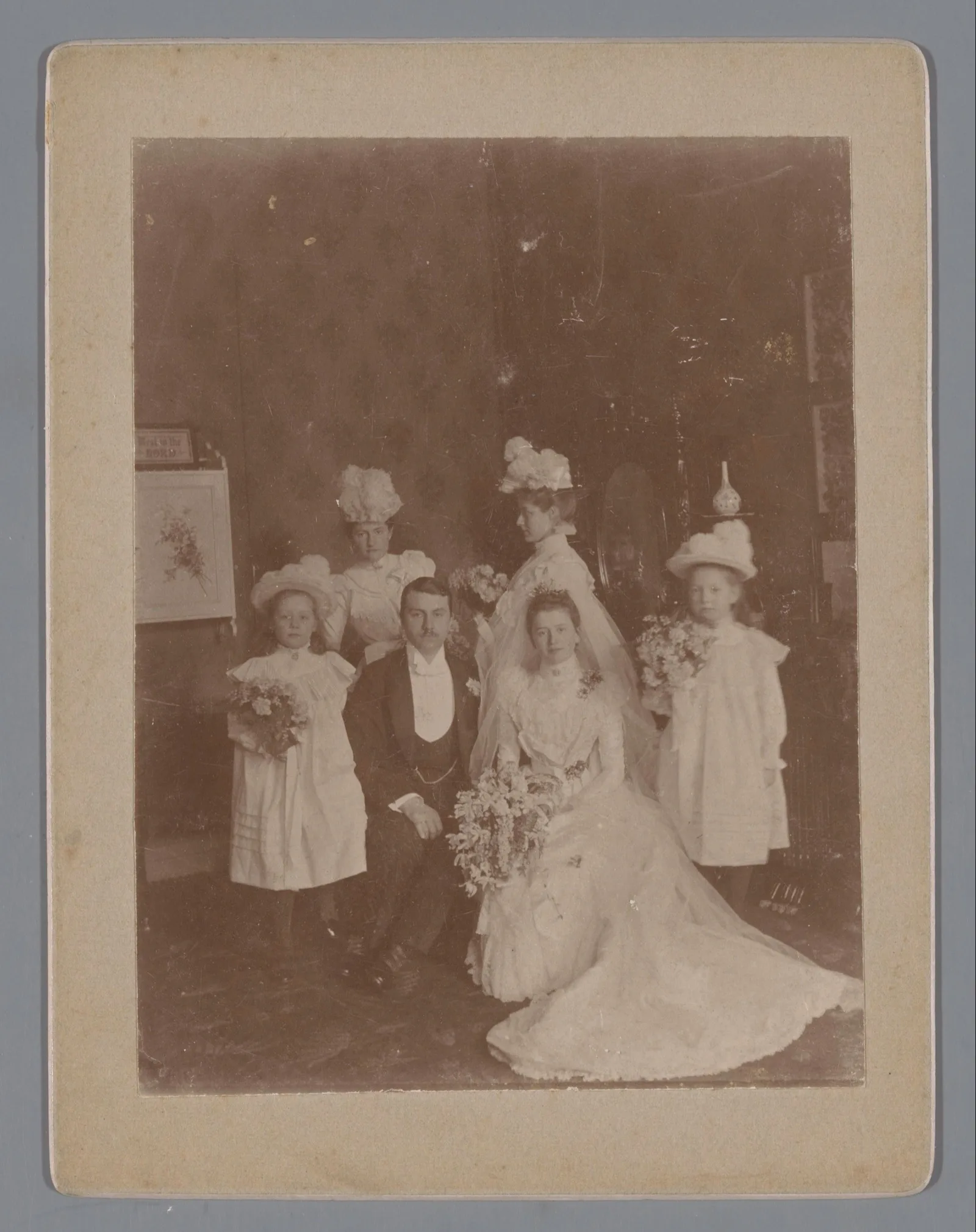 A bridal couple with four bridesmaids in matching dresses, studio portrait