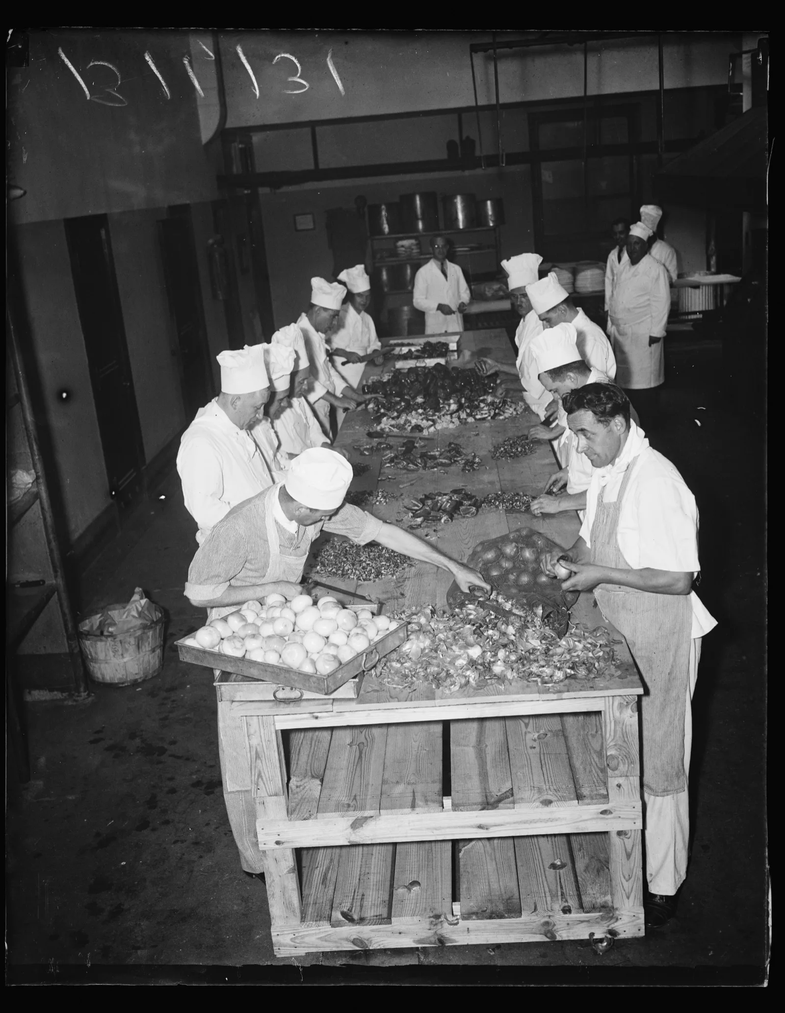 A cost accountant stands at the back of a hotel kitchen watching food being prepared for a banquet, Washington, 1936