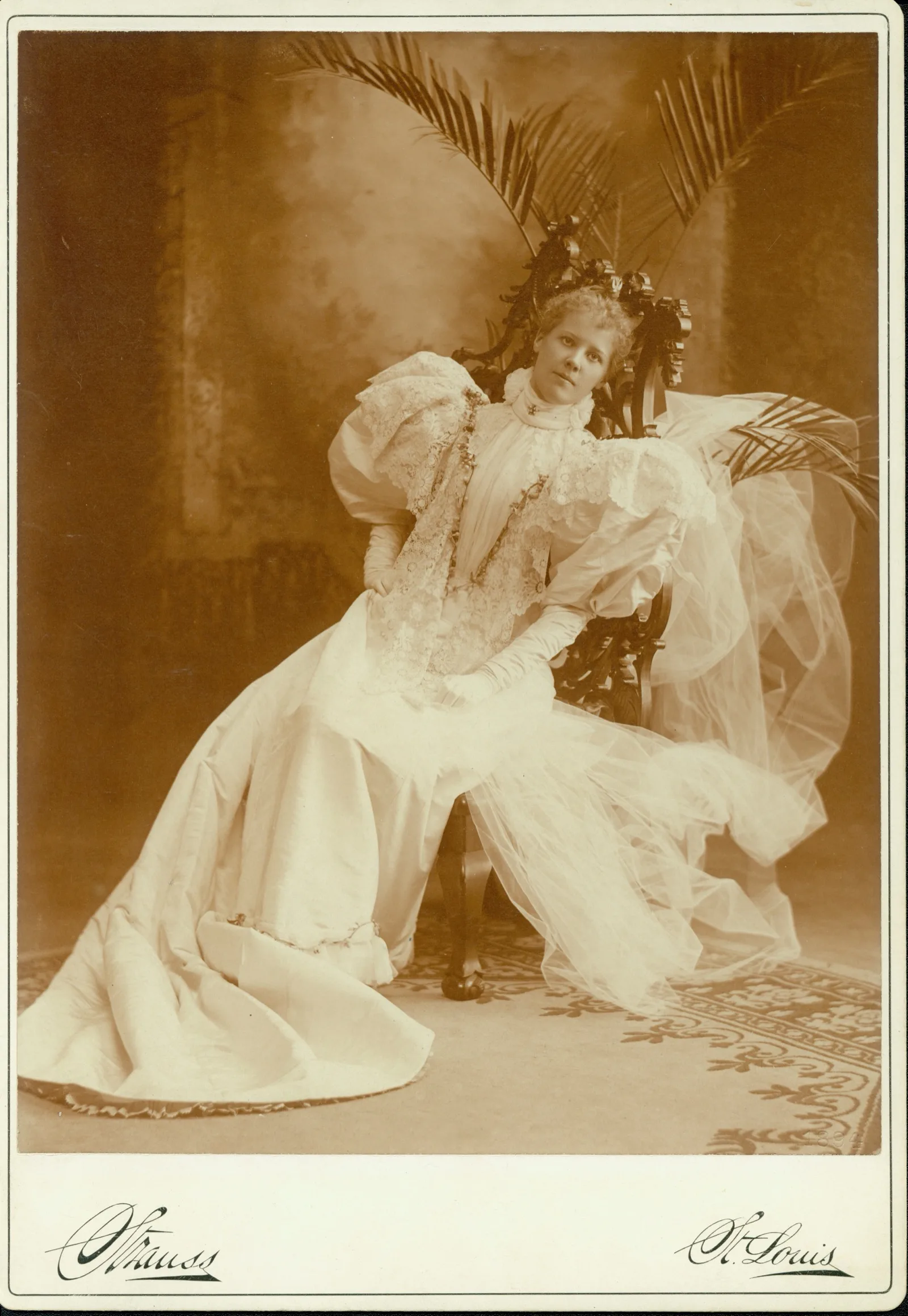A bride in a white gown with a long veil, studio portrait, 1894