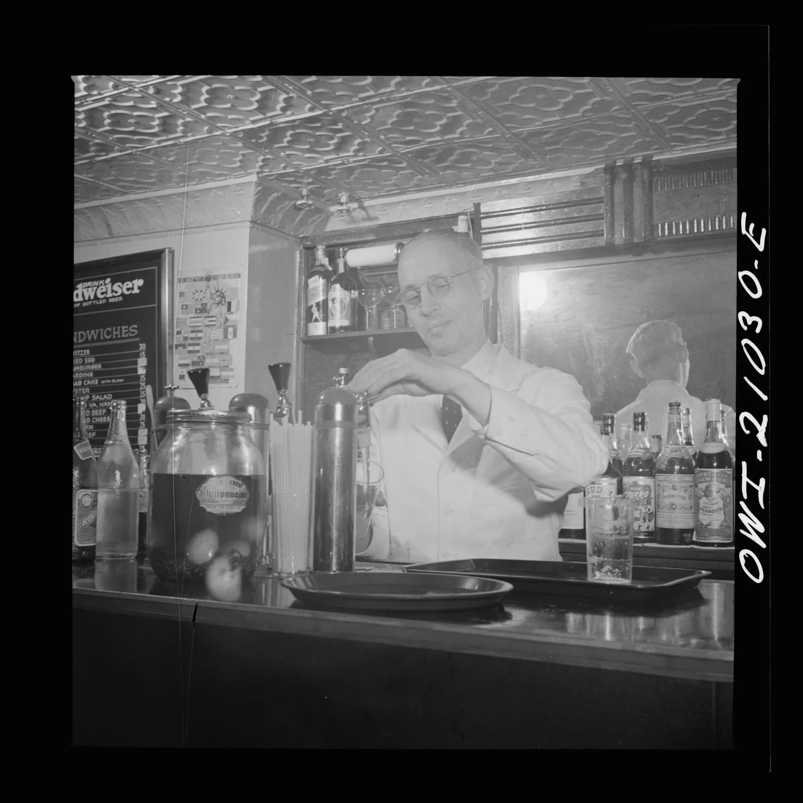 A bartender in a white jacket behind the bar of the Sea Grill, Washington, D.C., 1943