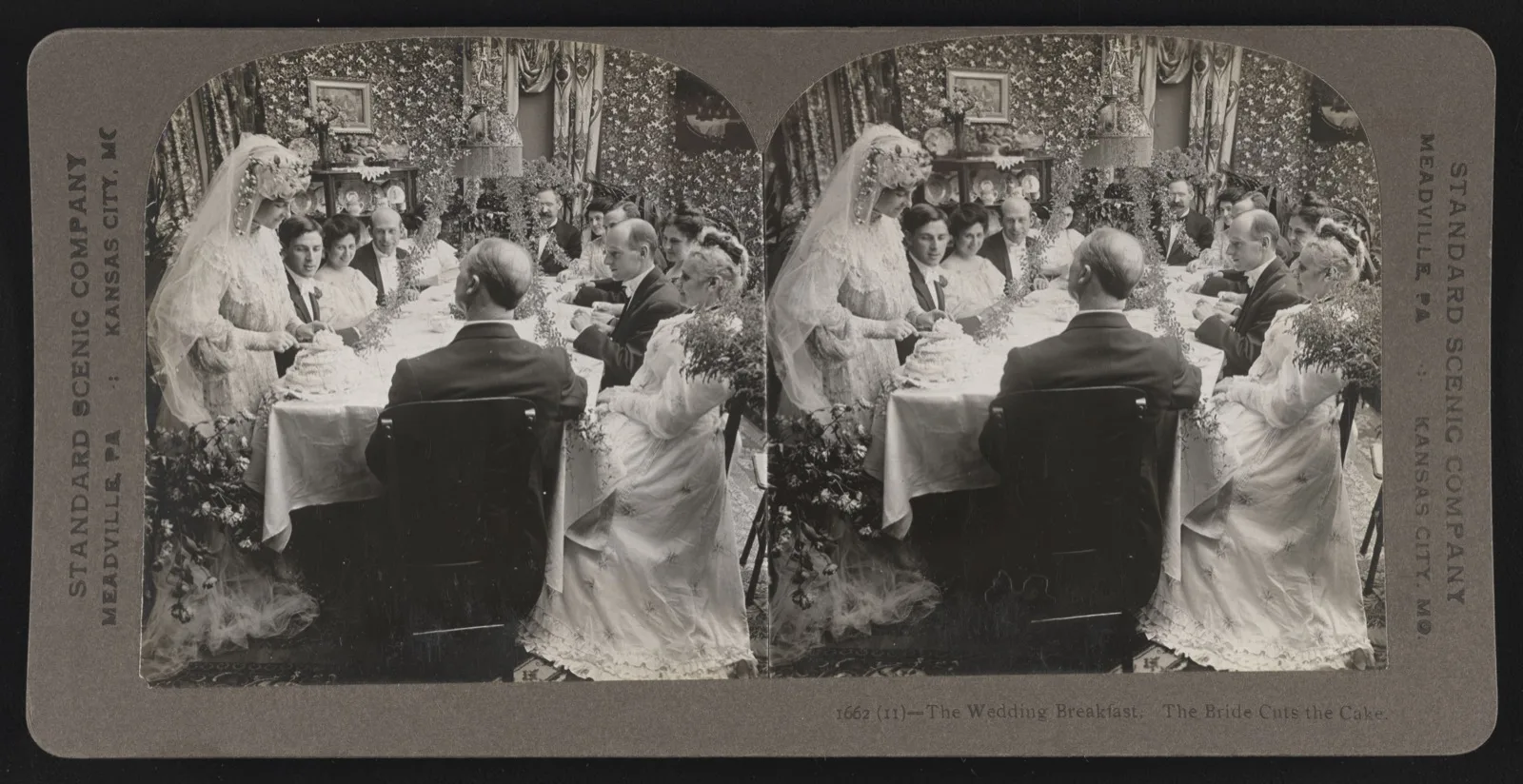 A 1906 stereograph of a bride in a veil cutting a wedding cake at a set table while the groom and guests look on
