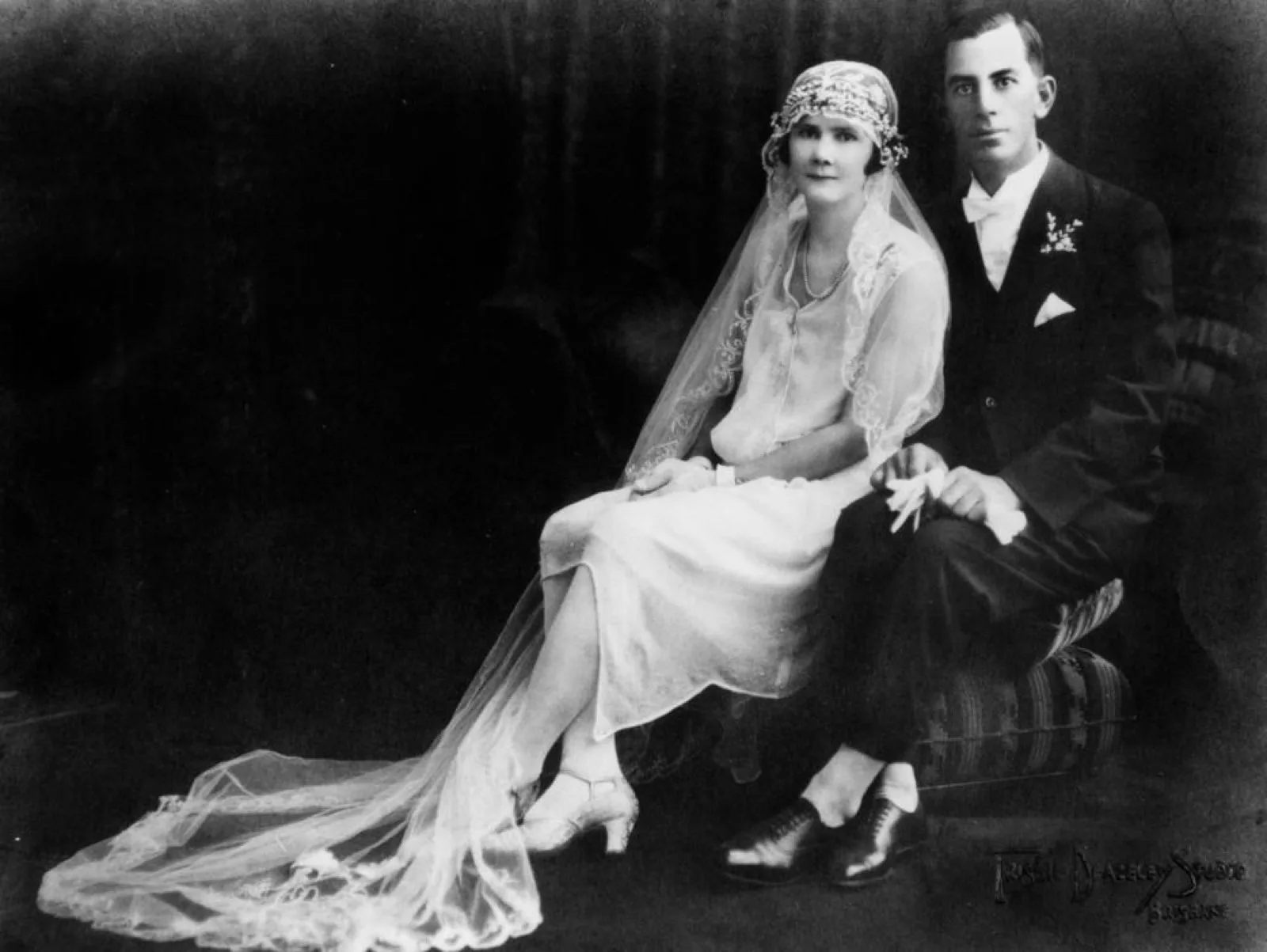 A 1920s bride and groom seated on cushions for their portrait